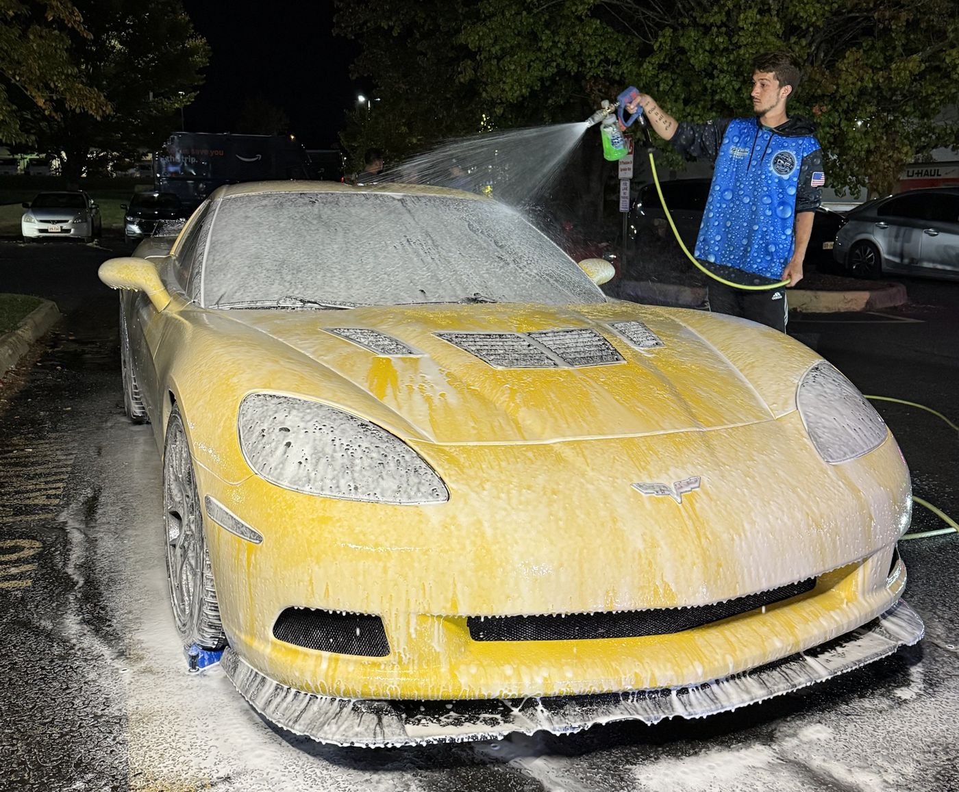 An All-In-One detailer foaming a yellow Corvette at night